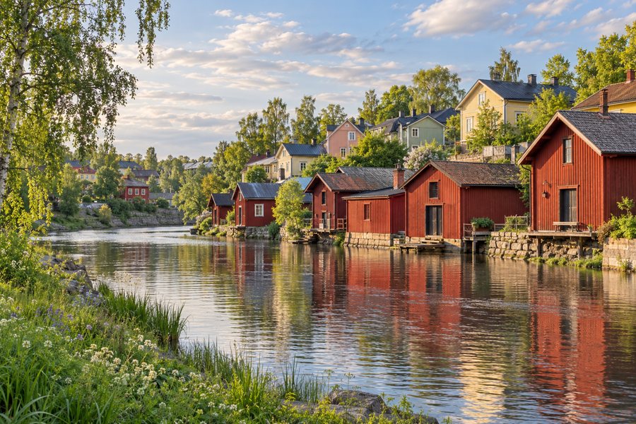 Symbolische Flussstadtkulisse mit roten Holzspeichern, Holzhäusern und Bäumen